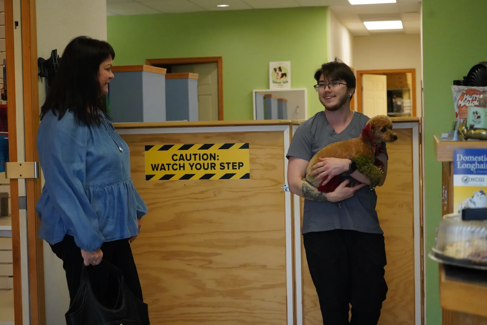A client being welcomed at the front desk while a groomer holds her puppy